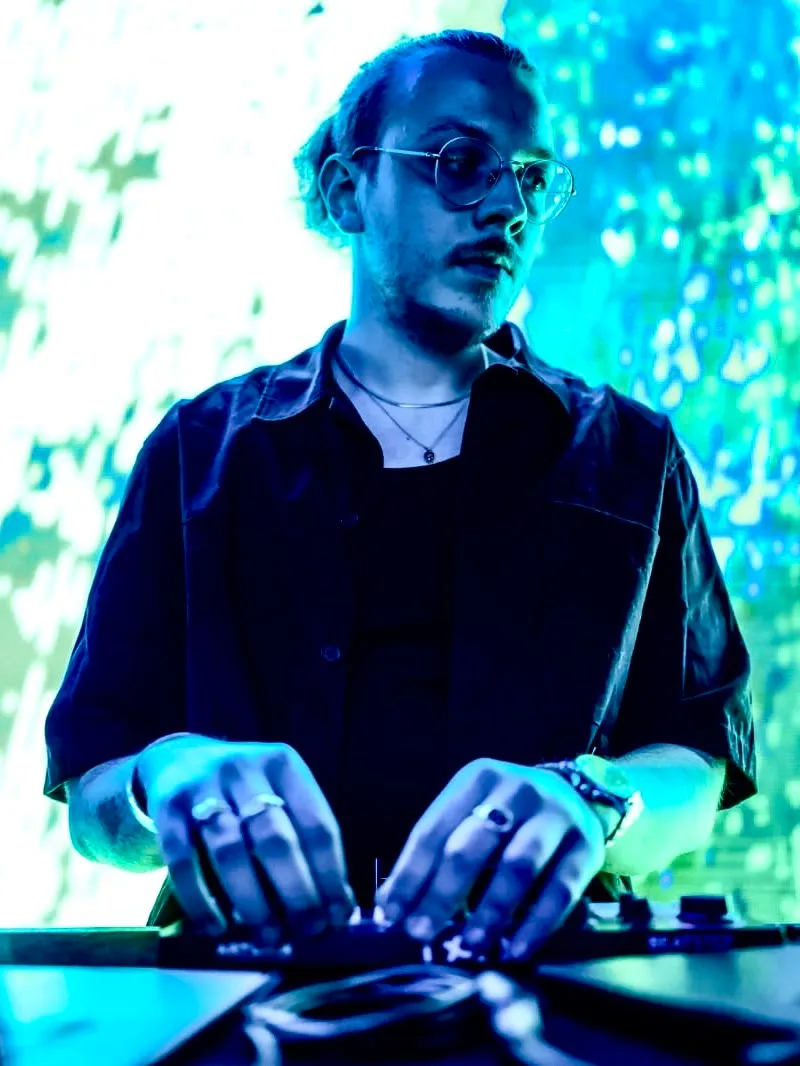 Ali Özgün Akyüz playing live at a laptop and controller, visuals projected behind him